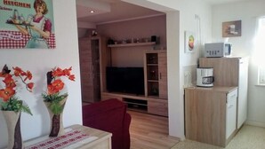 A compact living space with a television, wooden cabinets, a microwave, and a coffee maker.