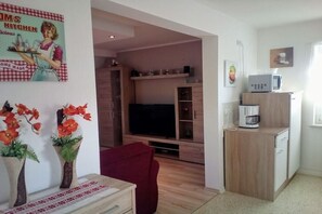A compact living space with a television, wooden cabinets, a microwave, and a coffee maker.
