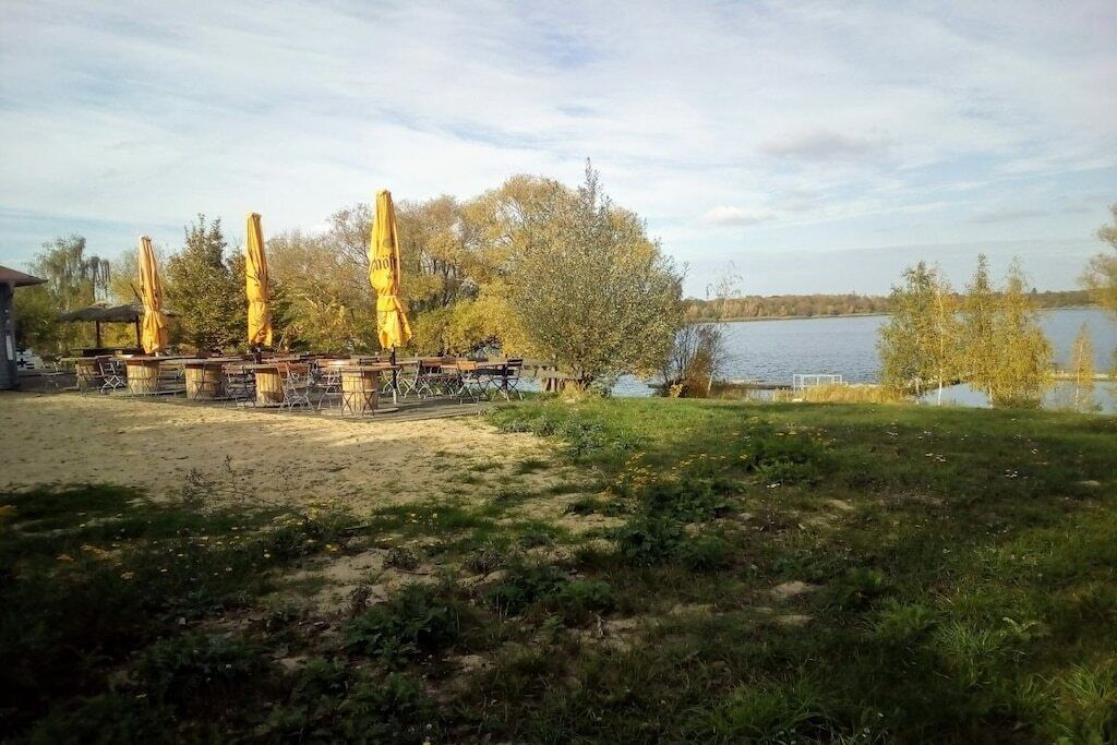 Ein Sitzbereich im Freien am Seeufer mit Sonnenschirmen und Tischen.