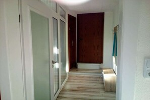 A hallway with a wooden floor, a glass door, and a wooden door. - Holiday apartment with 2 bedrooms (Markranstädt)