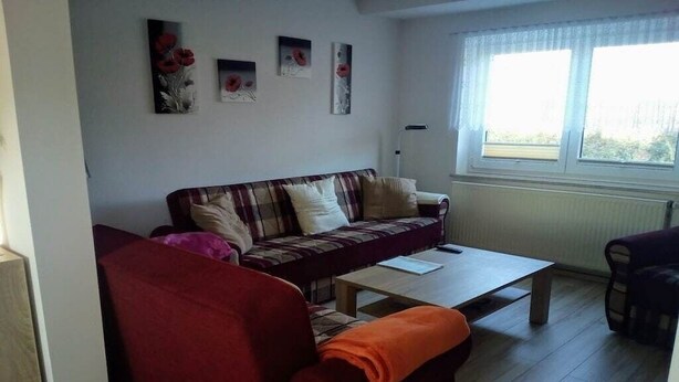 A living room with a sofa, a coffee table, and a window with curtains.