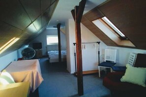 A room with a sloped ceiling, a bed, a chair, a table, and a radiator. - Holiday apartment with 2 bedrooms (Markranstädt)