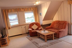 A cozy living room with two sofas, a coffee table, and a television. - Holiday apartment with 1 bedroom (Norden-Norddeich)