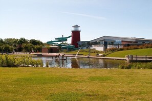 Un parc agrémenté d’un élément aquatique, d’un phare rouge et d’un bâtiment moderne.