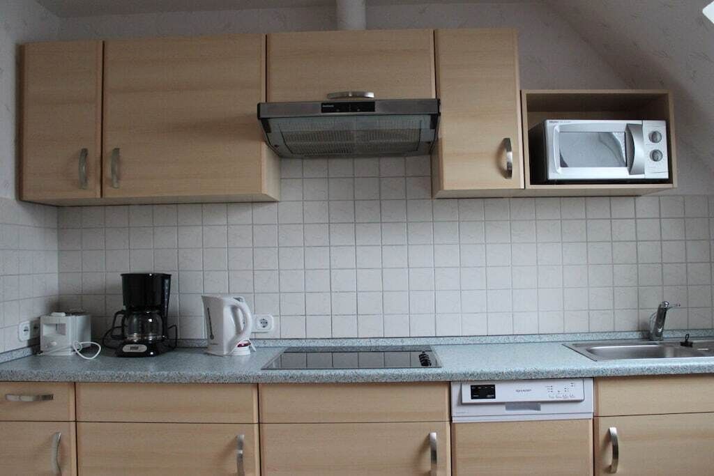 A kitchen with wooden cabinets, a microwave, a coffee maker, and a dishwasher.