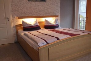 A bed with a headboard, two pillows, and a quilt. - Holiday apartment with 1 bedroom (Norden-Norddeich)