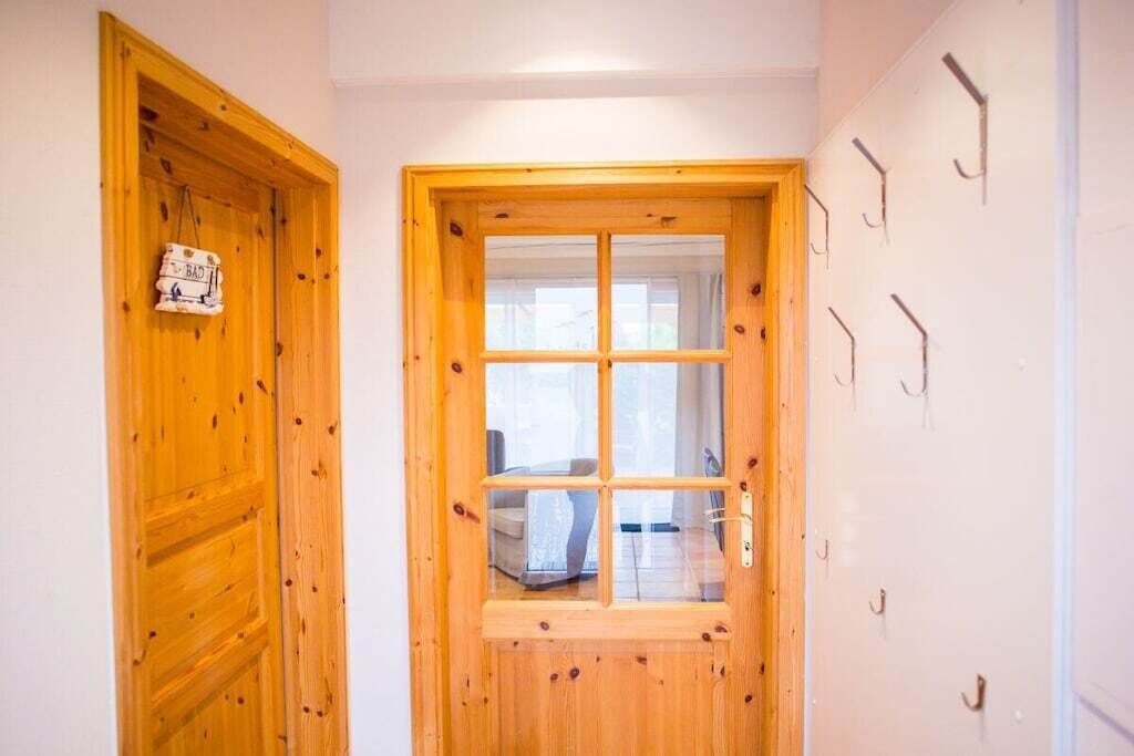 Una puerta de madera con un ventanal, un gancho en la pared y un letrero con la palabra 'BAD'.