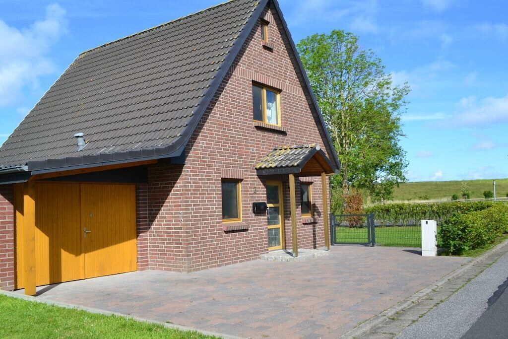 Un bâtiment à deux étages, construit en briques, avec un toit à pignon, une porte de garage et un petit porche.