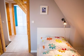 Ein Schlafzimmer mit einem Bett, einer Wandleuchte und einer Tür zu einem anderen Raum.