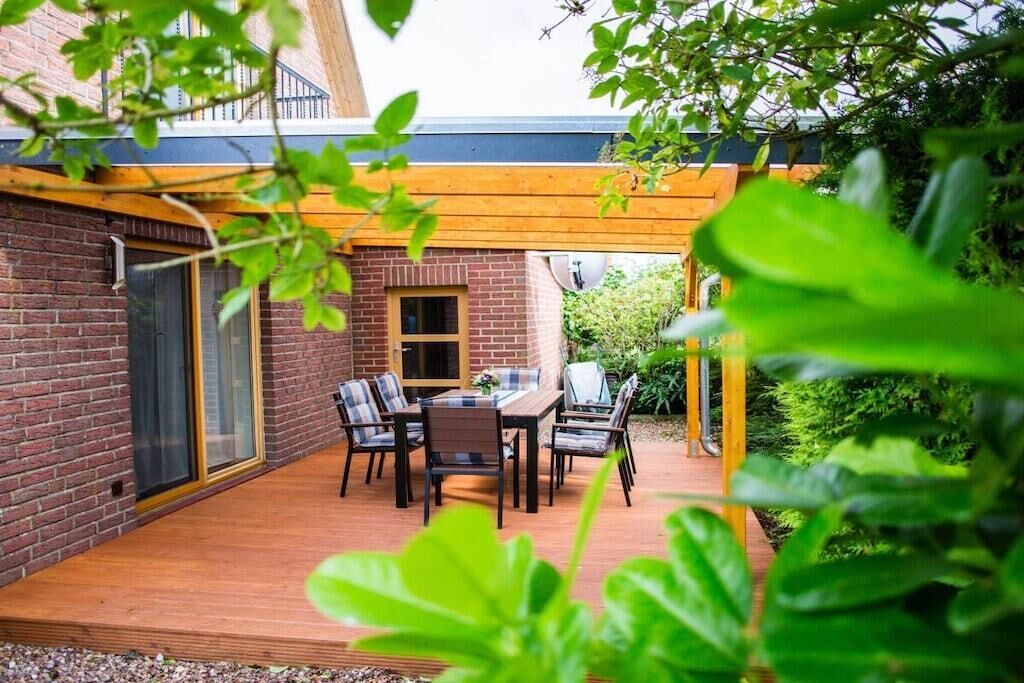 Une terrasse avec une table et des chaises, un mur en briques et une pergola en bois.