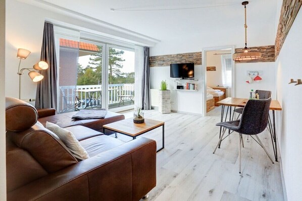 A modern living room with a sofa, a dining table, and a TV. - Villa by the sea, holiday apartment 8 (St. Peter-Ording)