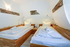 A hotel room with two wooden beds, white linens, and bedside lamps. - Villa by the sea, holiday apartment 8 (St. Peter-Ording)