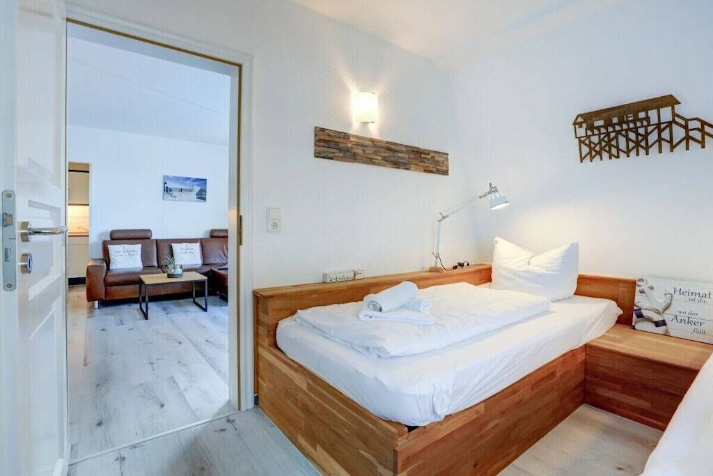 A bedroom with a wooden bed, a bedside lamp, and a wall-mounted light fixture.