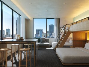 A modern hotel room with a city view, a desk with stools, a sofa, and a bunk bed. - FAV LUX NAGOYA MARUNOUCHI (Nagoya)