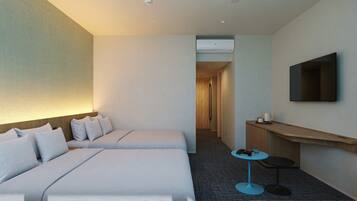 Habitación de hotel con dos camas, un televisor montado en la pared, una mesita con una taza y un escritorio con una silla.