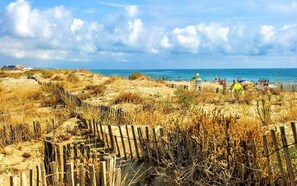 A beach with a wooden fence, sandy dunes, and a clear sky. - Vrbo Property (Le Barcarès)