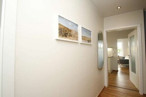 A hallway with a wooden floor, white walls, and two framed pictures. - "Sandplaat" in Uns to Hus (Juist)