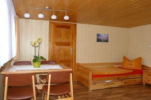 A compact room with a wooden bed, a small table with chairs, and a potted plant. - Holiday apartment with 2 bedrooms (Stubbenfelde)