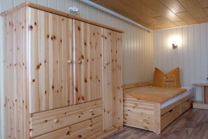A wooden room with a bed, a wardrobe, and a small table. - Holiday apartment with 2 bedrooms (Stubbenfelde)
