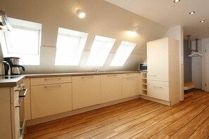 A modern kitchen with wooden flooring, white cabinetry, and skylights. - "Füürtoorn" at Uns to Hus (Juist)