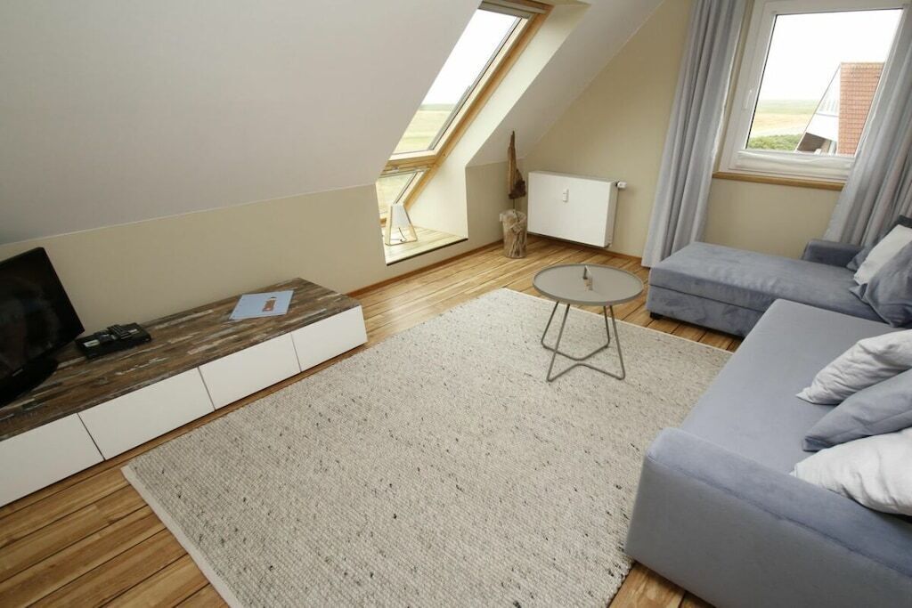 Ein modernes Schlafzimmer im Loft-Stil mit schrägem Dach, einer eingebauten Bettenlösung, einem kleinen runden Tisch und Blick durch ein Dachfenster.