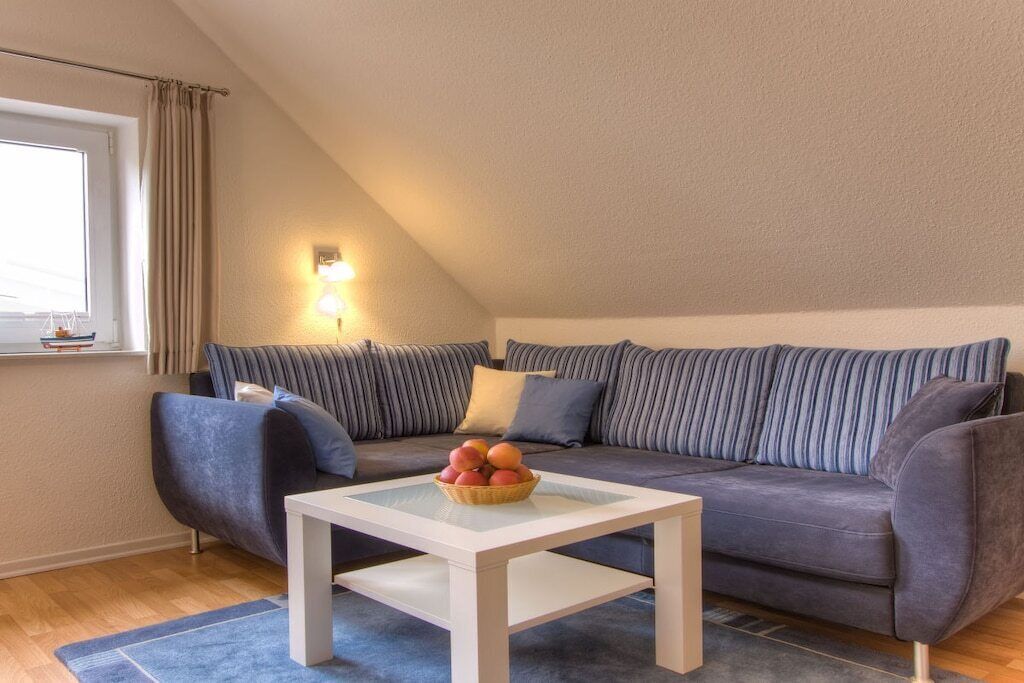 Un salon chaleureux avec un canapé, une petite table et un panier de fruits.