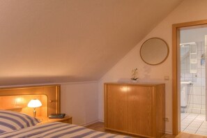A hotel room with a bed, a bedside lamp, a wooden wardrobe, and a bathroom visible through an open door. - at the Fock fruit farm - Hofblick (Mittelnkirchen)