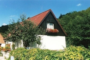 A single-story house with a red roof, white exterior walls, and a small balcony with red flowers. - "An der Bode" Apartment 1 (Altenbrak)