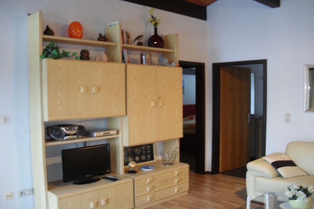 Ein Wohnzimmer mit Fernseher, Holzschränken und einer Couch.