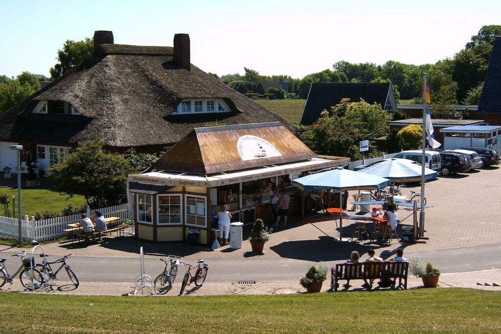 A traditional building with a thatched roof, a small shop with a sign, and outdoor seating.