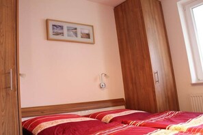 Ein Schlafzimmer mit einem Bett, einem Holzschrank, einer Wandleuchte und einem gerahmten Bild.