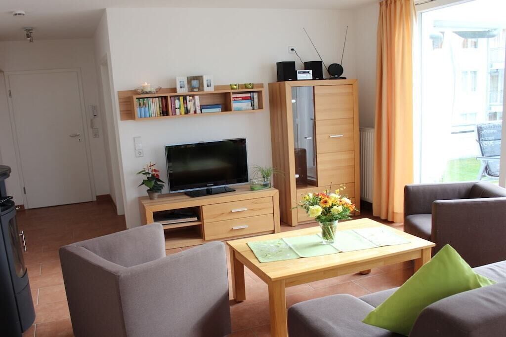 Una sala de estar con televisor, sofá, mesa de centro y estantería.