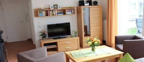 Una sala de estar con televisor, sofá, mesa de centro y estantería.