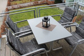Eine Terrasse mit Tisch und Stühlen, einer Laterne und Blick auf einen Garten.