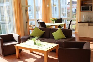 A modern living room with a sofa, chairs, a coffee table, and a dining area with a table and chairs. - Holiday apartment with 2 bedrooms (Großenbrode)