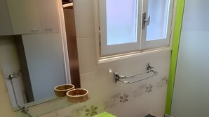 Une salle de bain avec un lavabo blanc, un plan de toilette vert et un miroir au-dessus.