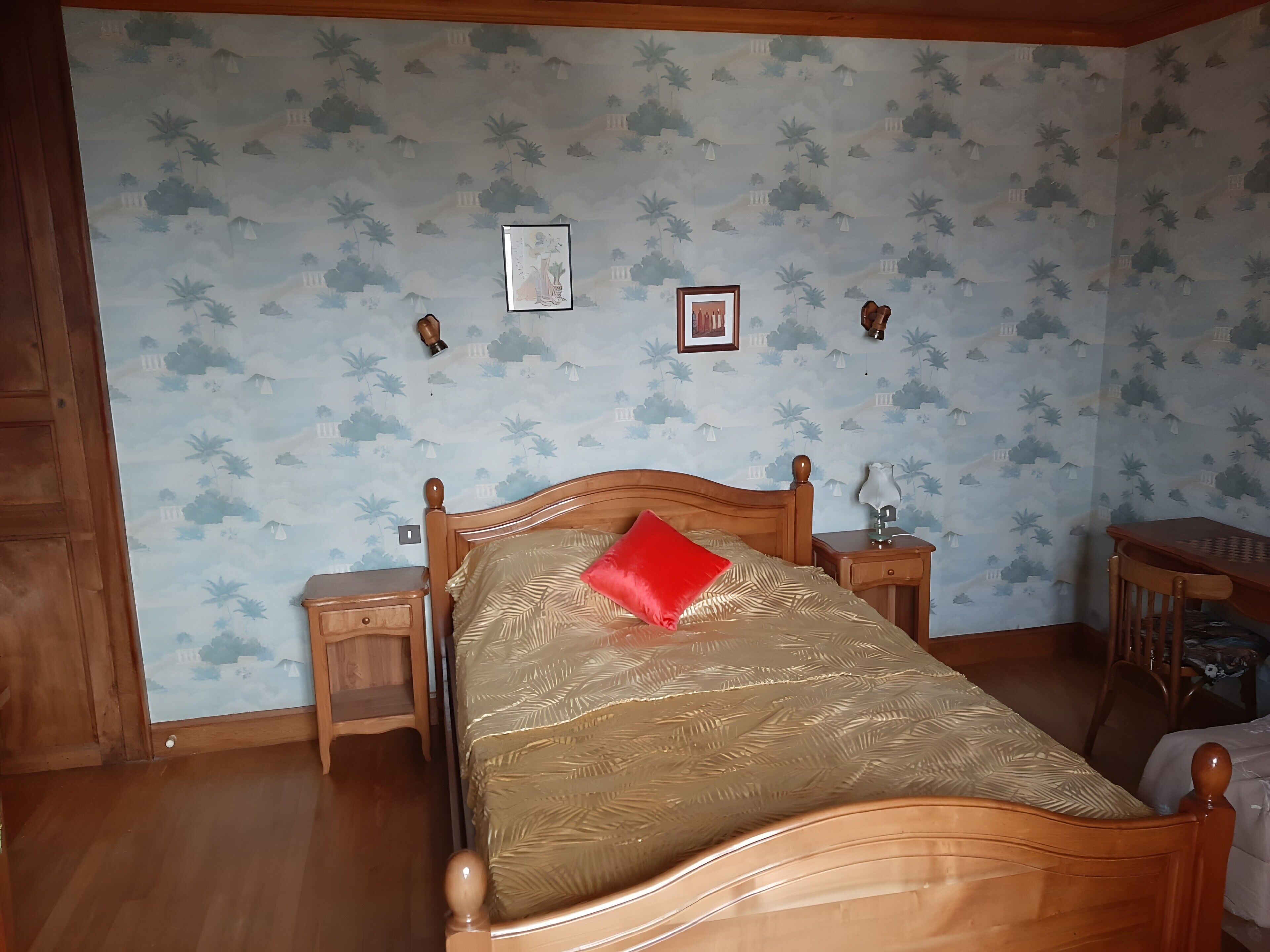 Une chambre à coucher avec un lit en bois, deux tables de chevet, une lampe et une petite table.