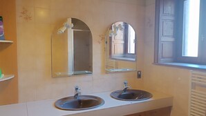 Une salle de bain avec deux lavabos, un miroir au-dessus de chacun, et une fenêtre sur le côté droit.