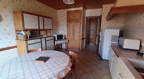 A compact kitchen with a dining table, a microwave, a refrigerator, and wooden cabinets. - Detached village house with balcony, near Issoire and natural attractions (Perrier)