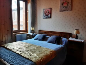 A bedroom with a bed, two bedside tables with lamps, a radiator, and a window with curtains. - Detached village house with balcony, near Issoire and natural attractions (Perrier)