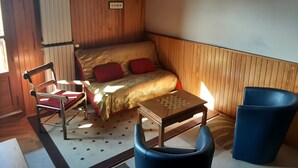 Une petite pièce comprenant un lit, une chaise, une petite table et un radiateur.