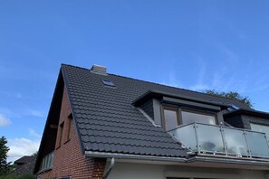 A residential building with a sloped roof, a visible attic window, and a balcony with a glass railing. - Apartment building "Albatros" (St. Peter-Ording)