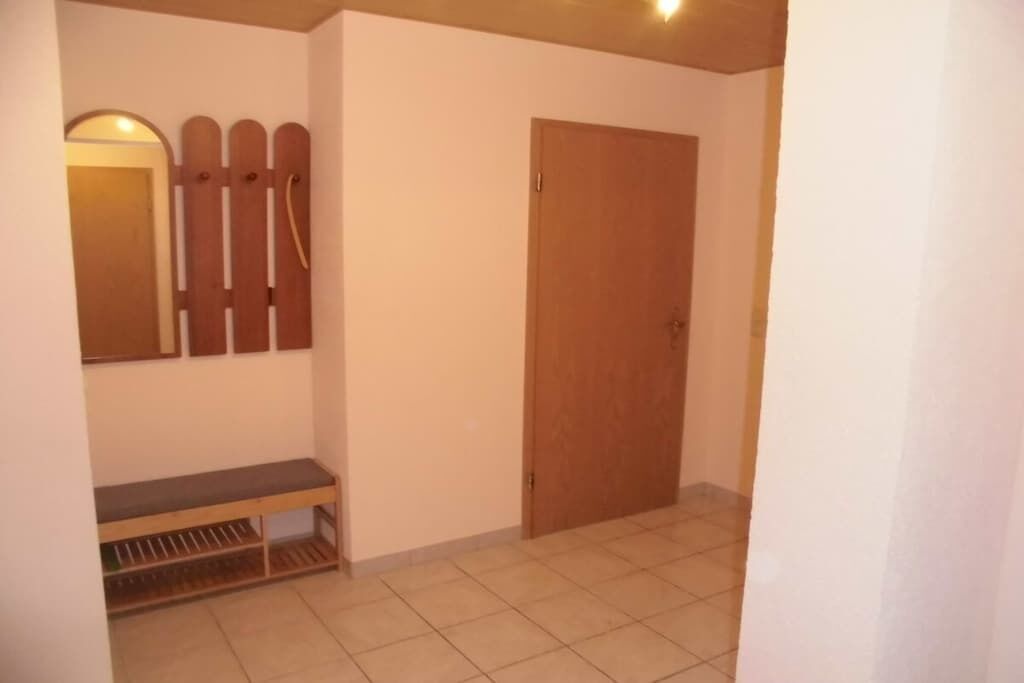 A hallway with a bench, a door, and a wall-mounted rack.