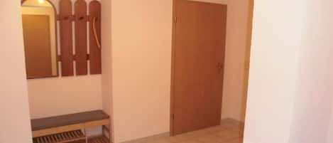 Un pasillo con un banco, una puerta y un perchero en la pared.