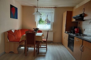 Eine kompakte Küche mit Essbereich, ausgestattet mit einem Holztisch, Stühlen und einem eingebauten Ofen.