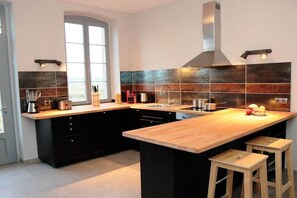 Eine moderne Küche mit Kochinsel, schwarzen Schränken und einem großen Fenster.