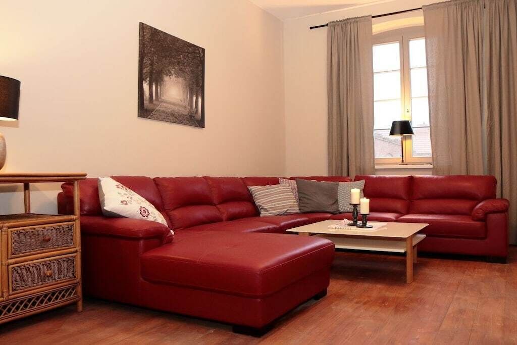 A living room with a red sofa, a wooden coffee table, and a lamp.