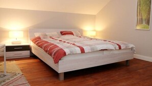 Quarto com cama, mesas de cabeceira, tapete e quadro pendurado na parede.