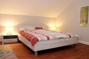 A bedroom with a bed, nightstands, a rug, and a wall-mounted painting. - Erbschulzenhof (Müritz) 6 Pers. (Buchholz (Müritz))