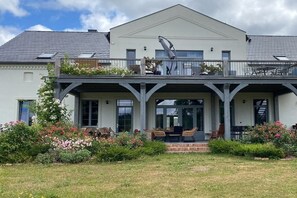 A two-story house with a covered patio area, a garage, and a garden with flowering plants. - Erbschulzenhof (Müritz) 6 Pers. (Buchholz (Müritz))